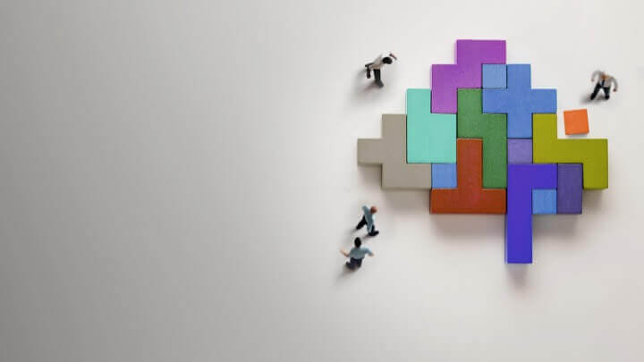 Men building space invaders robot out of colourful blocks